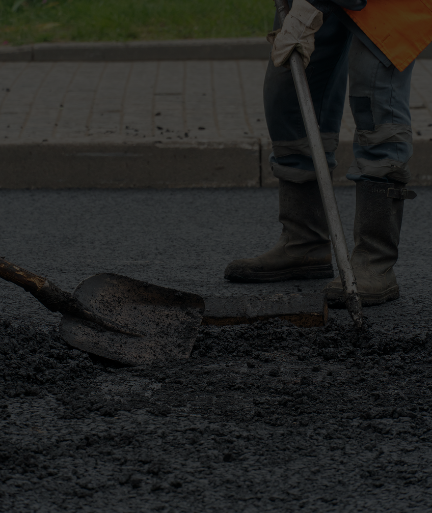 Worker repairing road with asphalt.